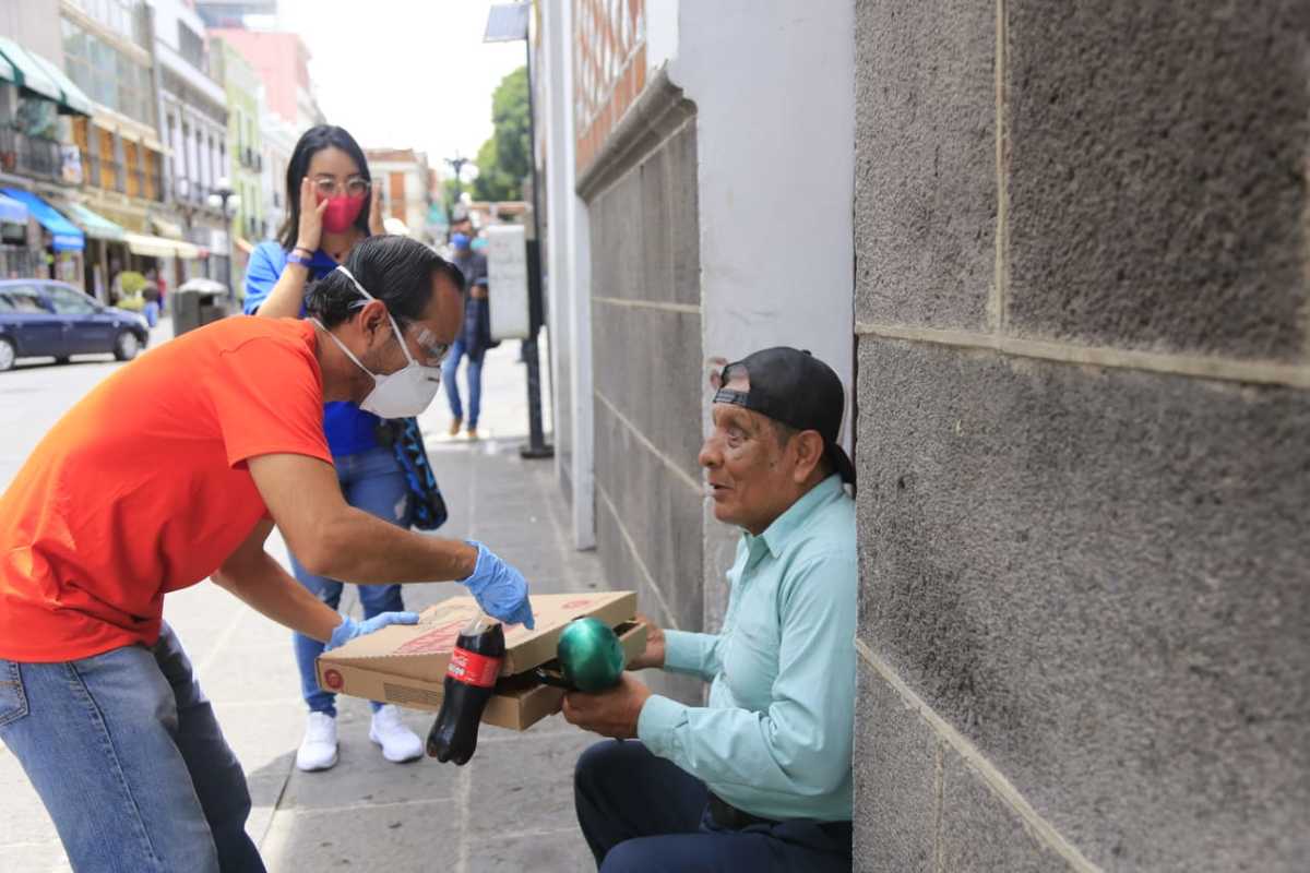 Rafael Deeyss, conocido como Rafa Activista, le entrega una pizza y una "coca" a una persona invidente que canta para ganarse la vida. (Andrés Lobato)