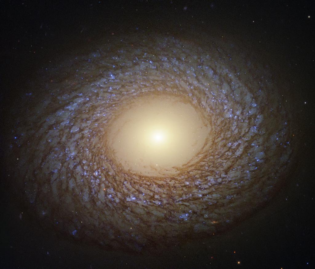 La galaxia NGC 2775 tiene millones de estrellas azules brillantes en los complejos brazos espirales en forma de pluma. (NASA)