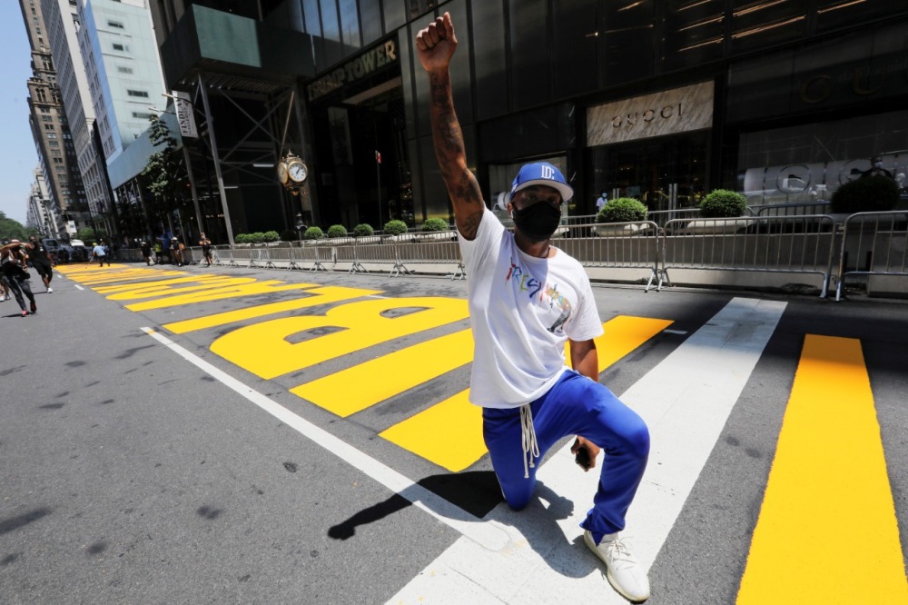 Ian Millin, de la ciudad de Nueva York, se arrodilla y levanta el puño sobre el mural recién pintado. (Reuters)