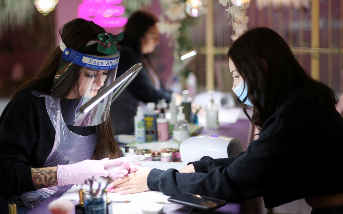 Una mujer trabaja en la manicura de una cliente en el salón Nails by Annabel en Newcastle-under-Lyme, Gran Bretaña. (Reuters)