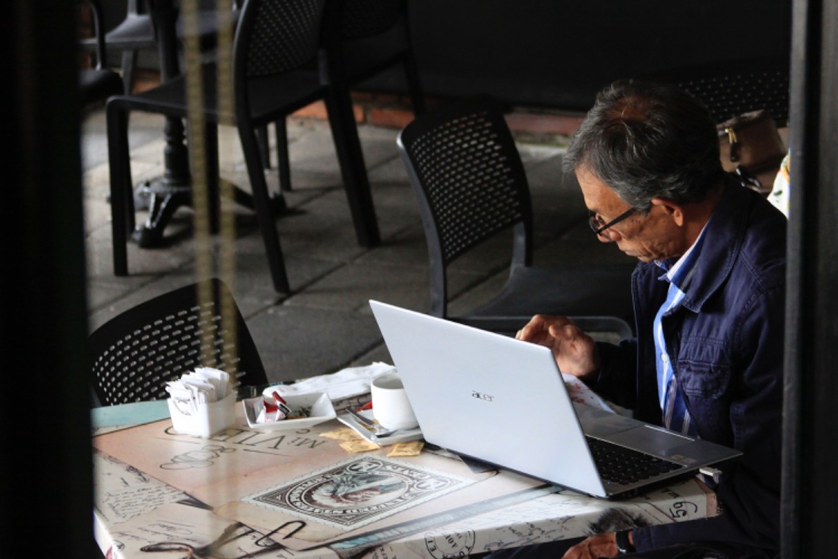 Un hombre trabaja con su computadora en la terraza, a nivel de calle, de un restaurante. (Andrés Lobato)