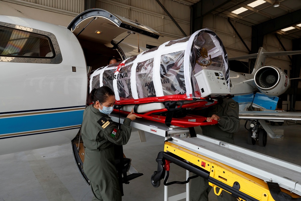 Oficiales equipan una ambulancia aérea de la Marina. (EFE)