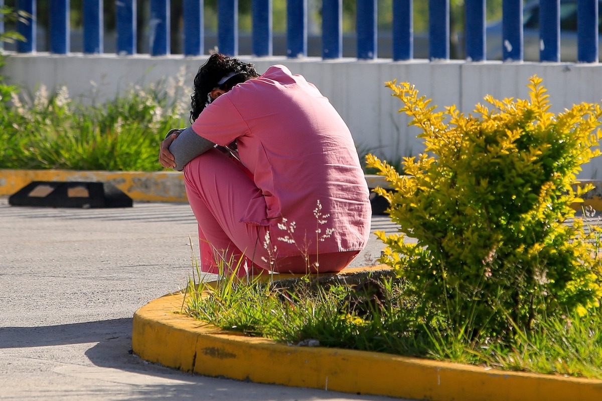 Una trabajadora del sector salud sale un momento para sentarse en una banqueta al exterior del Hospital donde trabaja. (Andrés Lobato)