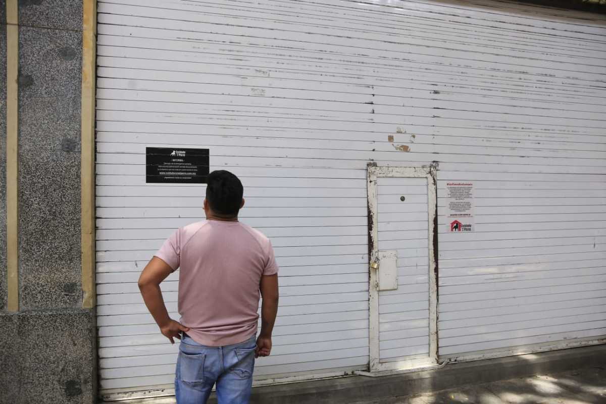 Un hombre lee un letrero donde se anuncia la próxima reapertura de un negocio. (Andrés Lobato)