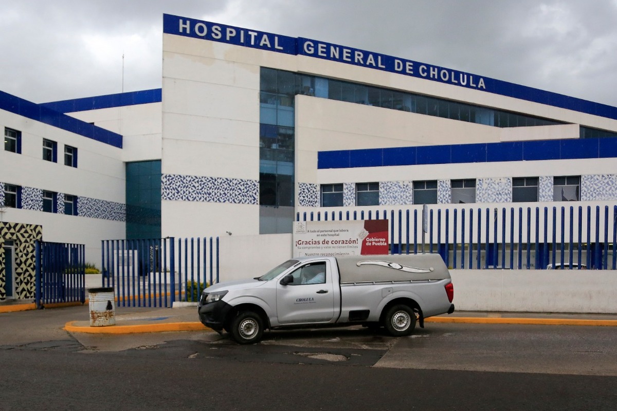 Bajo la lluvia, personal de una funeraria espera al exterior del Hospital General de Cholula. (Andrés Lobato)