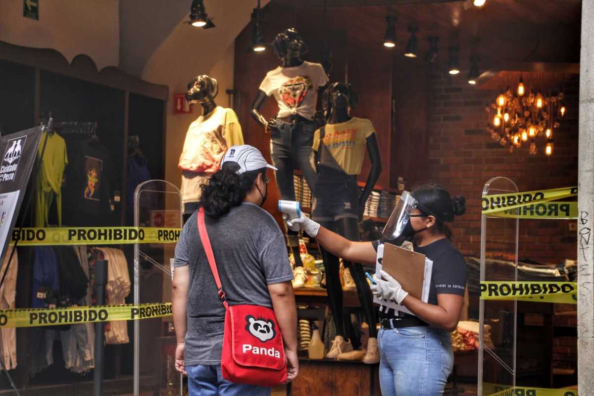 Empleada de una tienda departamental toma la temperatura a cliente. (Melanie Torres)