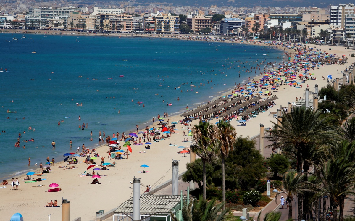 La gente toma el sol y nada en la playa de El Arenal en Palma de Mallorca, España. (Reuters)