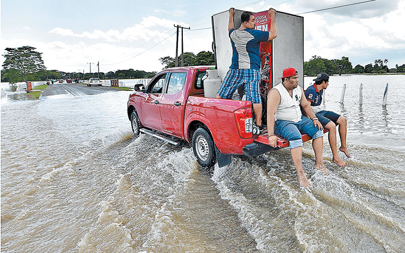 Tres hombres rescatan pertenencias en una localidad tabasqueña. (EFE)