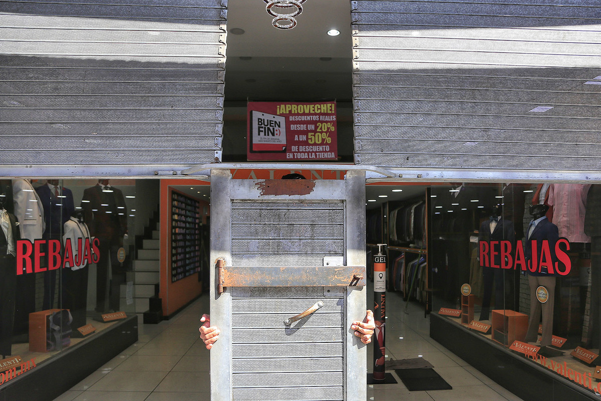 Empleado de tienda de ropa, donde se percibe un cartel promocionando las compras del Buen Fin. (Andrés Lobato)