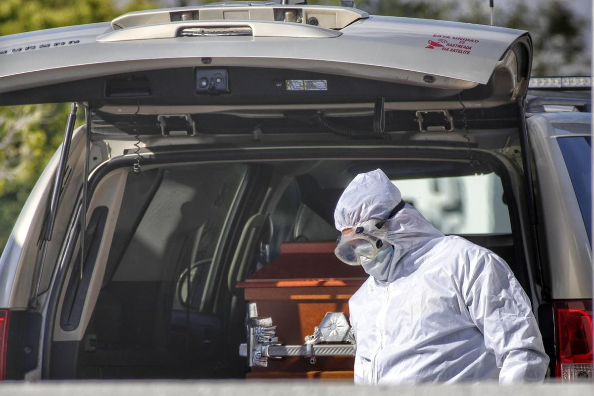 Trabajador de una funeraria recoge el cuerpo de una víctima del covid-19. (Melanie Torres)
