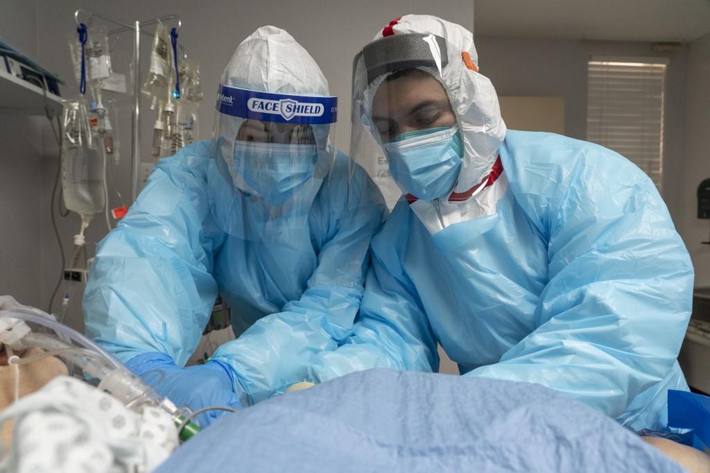 El rostro de los médicos está cubierto, por lo que algunos llevan una fotografía suya colgada en el cuello. (AFP)