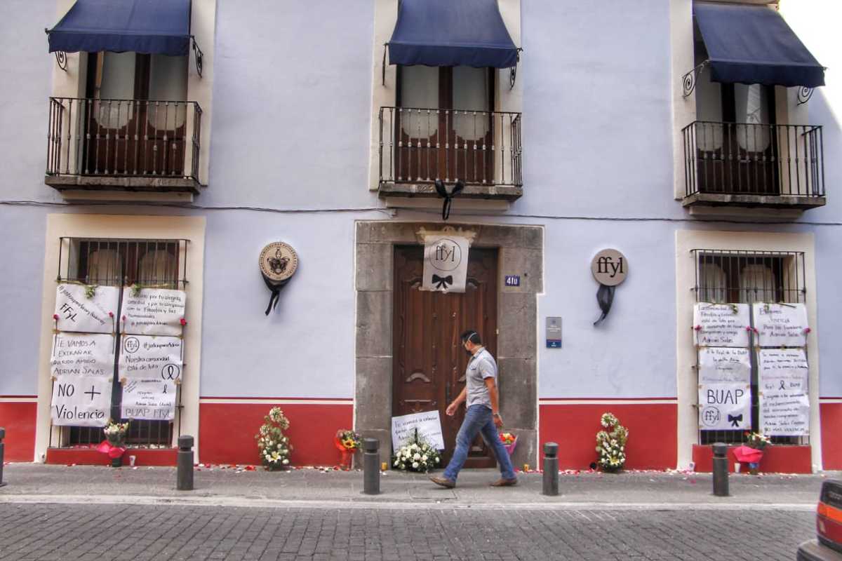 Flores, pancartas y moños negros colocados en un edificio de la facultad de filosofía y letras de la BUAP. (Melanie Torres)