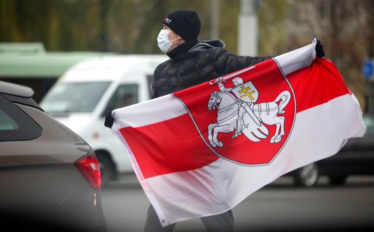 Un hombre sostiene una bandera bielorrusa durante una manifestación en Minsk. (AP)