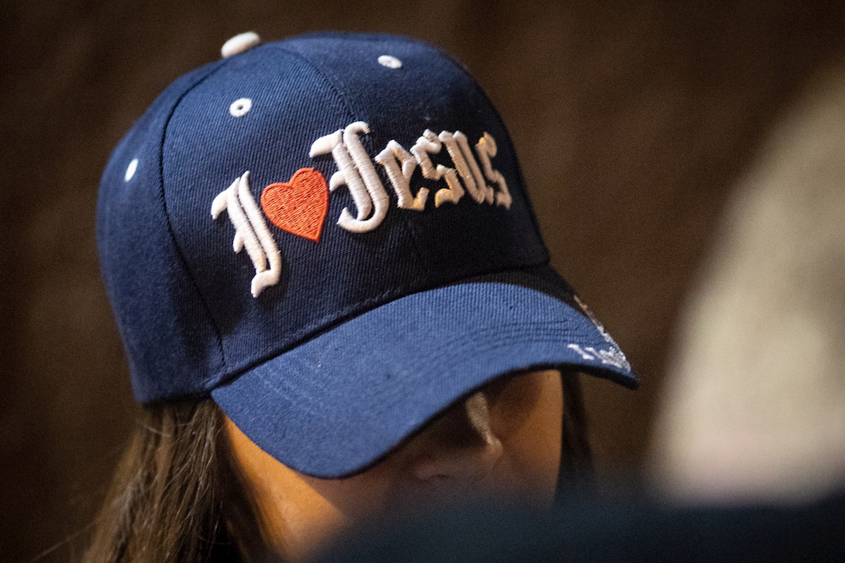 Una mujer del grupo cristiano "Let Us Worship" usa una gorra con leyenda de adoración a Cristo. Foto: Christian Monterrosa/EFE