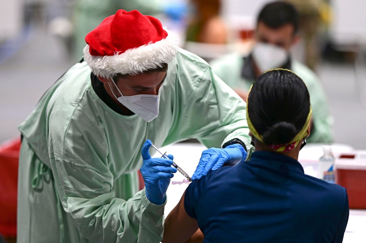 Un trabajador de salud con un gorro navideño administra una vacuna contra coronavirus. (AP)