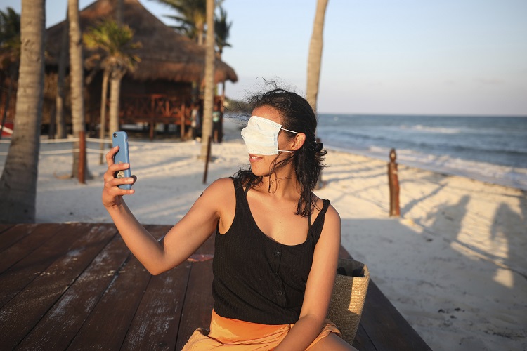 Turista se toma cubriéndose los ojos con un tapabocas en Playa del Carmen. (AP)