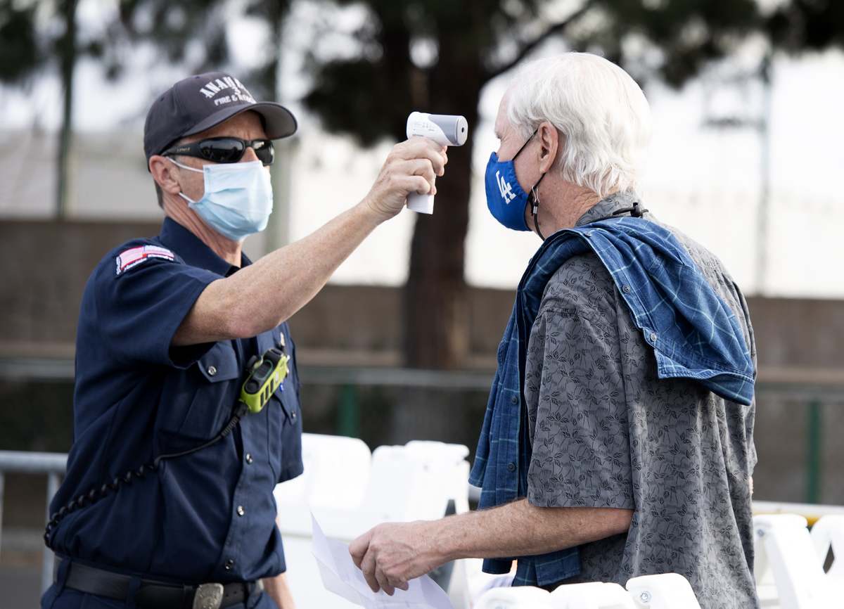 A un hombre le toman la temperatura antes de entrar a recibir su vacuna anticovid en el estacionamiento de Disneyland California. Foto: Valerie Macon/