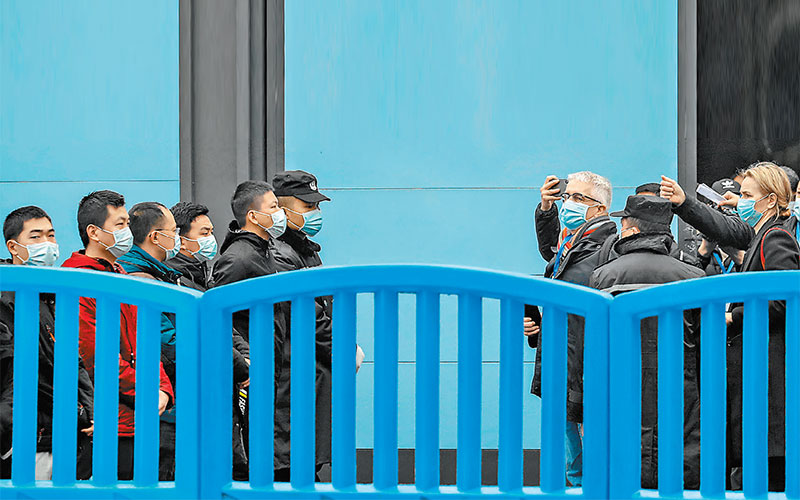 Personal de seguridad vigila mientras miembros de la OMS visitan el mercado mojado de Wuhan para investigar los orígenes de la pandemia. (Reuters)