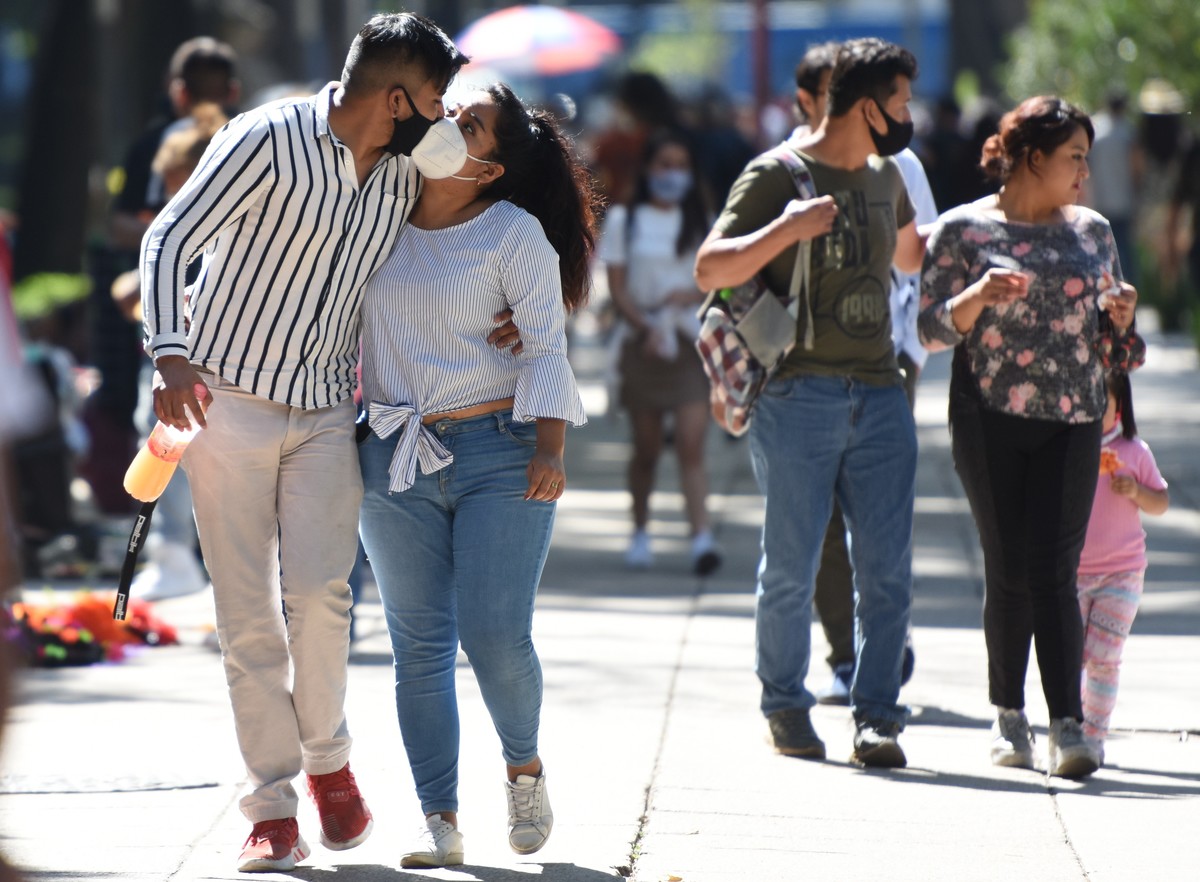 Una pareja camina por Paso de la Reforma mientras se da un beso utilizando el cubrebocas | Cuartoscuro