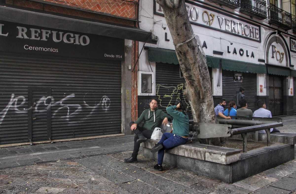 Un par de personas platican sin cubrebocas en el Centro Histórico de Puebla. (Melanie Torres)