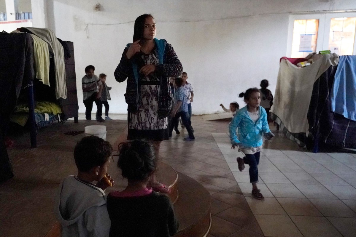 Una mujer hondureña que espera para entrar a Estados Unidos, se peina mientras sus unos niños juegan cerca | AP
