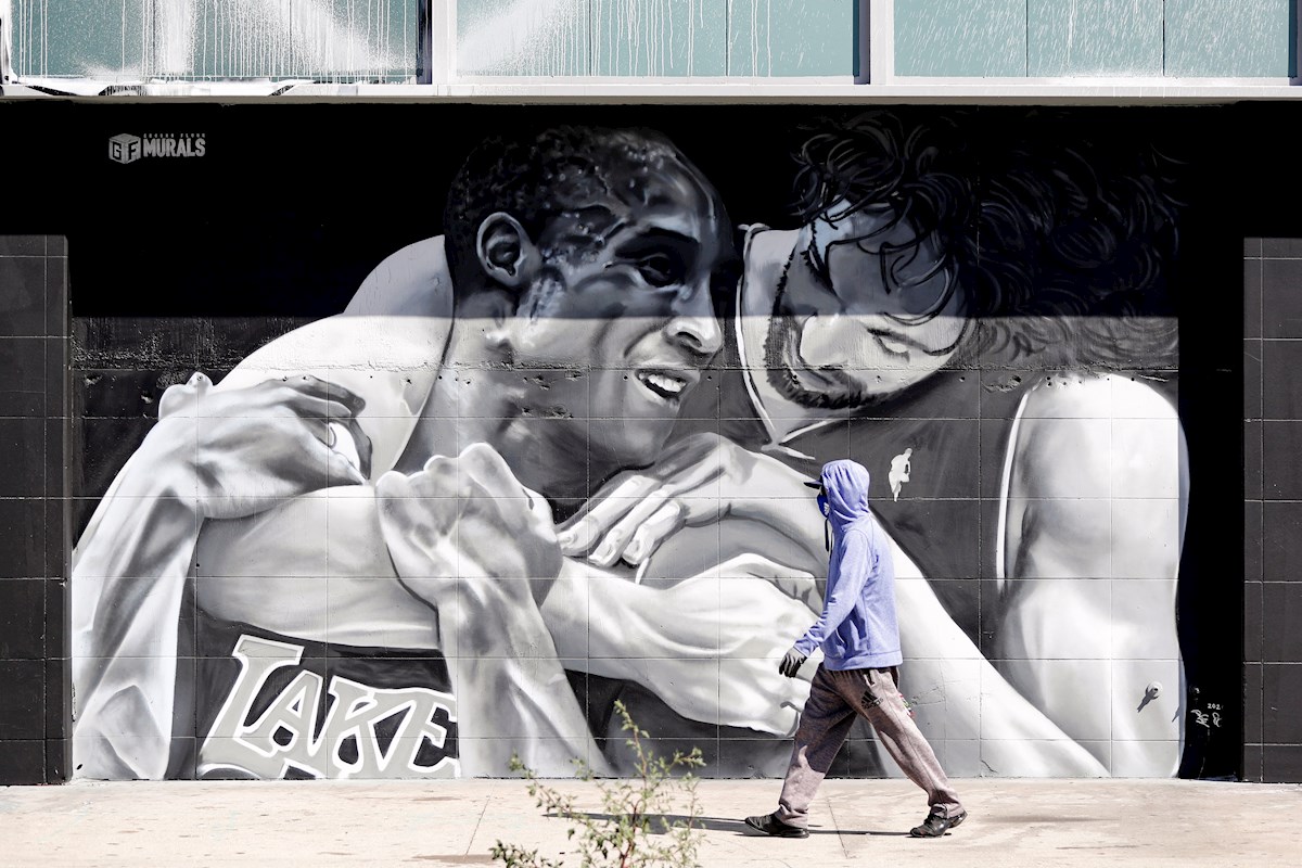 Un peatón camina frente a un mural de los jugadores de Los Lakers. Foto: Étienne Laurent/EFE