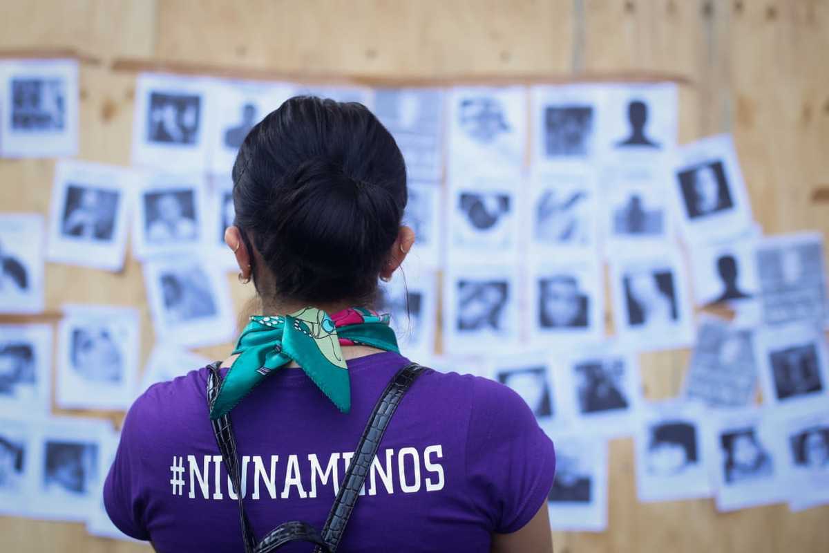 Mujer mira fotografías de mujeres asesinadas colocadas en muro de madera en CdMx | Araceli López