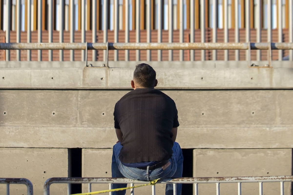 Un migrante mira el muro fronterizo muy cerca de la aduana de San Ysidro. (Andrés Lobato)