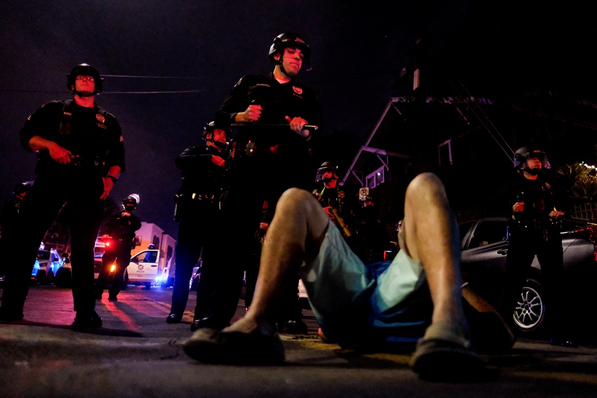Un hombre yace en la calle frente a la policía durante las protestas en Echo Park. Foto: Ringo Chiu/AFP
