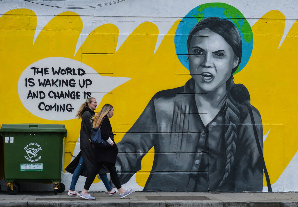 Dos jóvenes mujeres caminando por el mural de Greta Thunberg en Dublin, Irlanda.