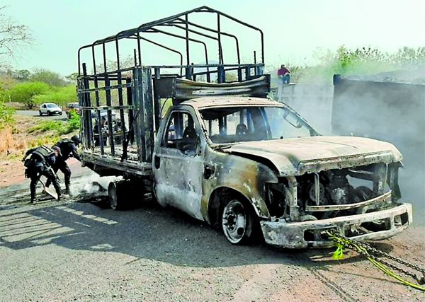 Policías extinguen una camioneta utilizada por los sicarios. Especial