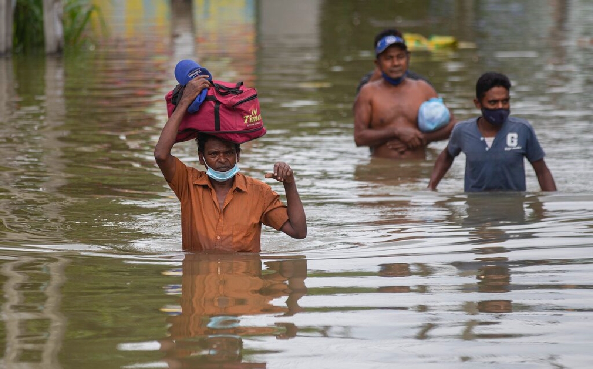Varias personas caminan por una calle inundada tras las fuertes precipitaciones en Malwana. (AP)
