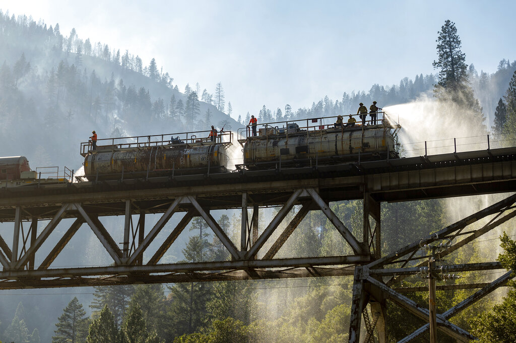 Bomberos rocían agua desde un tren antincendios para combatir el fuego en el Bosque Nacional Plumas. (Noah Berger/AP)