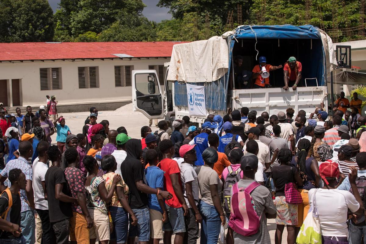 Personas esperan para recibir comida que repartiría el Programa Mundial de Alimentos, este viernes en Camp Perrin. (EFE)