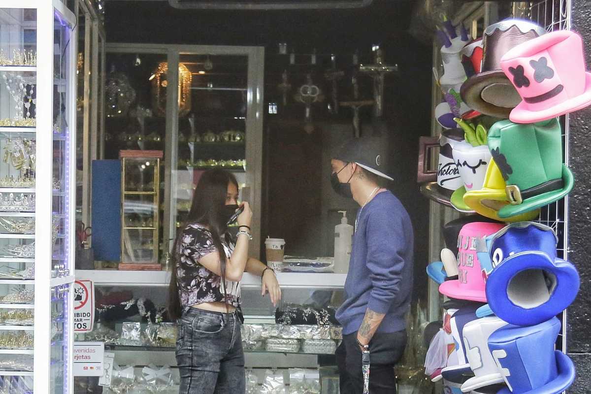 Dos empleados de una tienda de regalos platican en la entrada de un negocio | Andrés Lobato