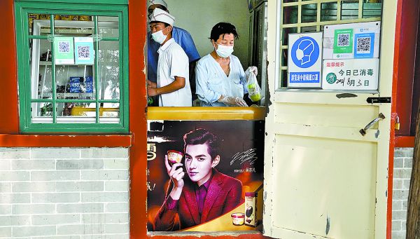 Vendedores de comida detrás de un refrigerador con un afiche de la estrella pop chino-canadiense Kris Wu. Ng Han Guan/Ap