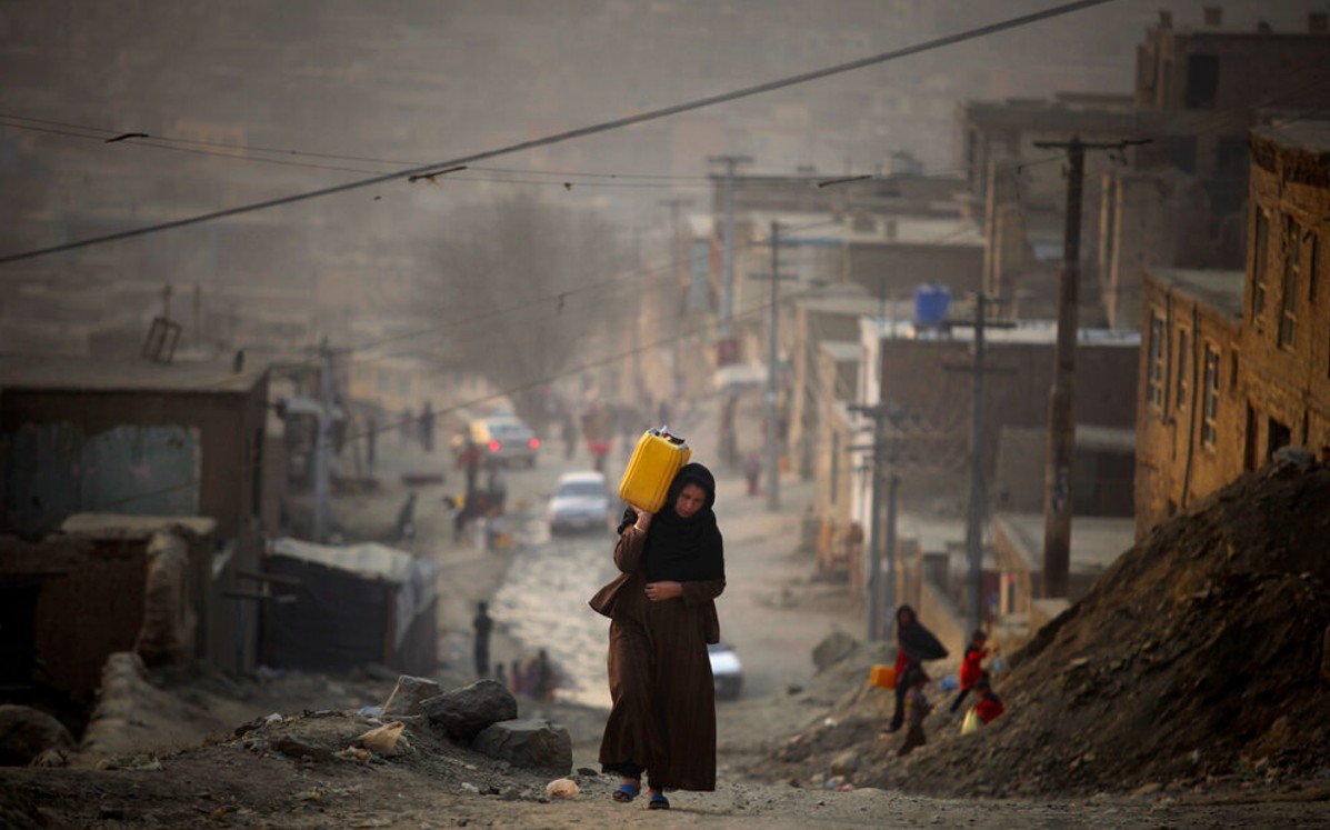 Mujer carga  contenedor con agua mientras camina hacia su casa en Kabul, Afganistán | AP/ Archivo