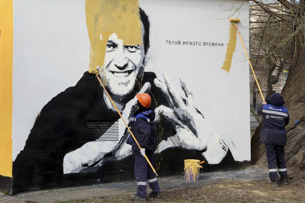 Trabajadores municipales pintan sobre una imagen del encarcelado líder opositor ruso Alexei Navalny en San Petersburgo | AP