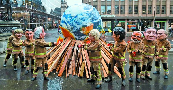 Manifestantes de la organización Oxfam parodian en las calles de la ciudad escocesa a los principales líderes del mundo prendiéndole fuego al planeta.