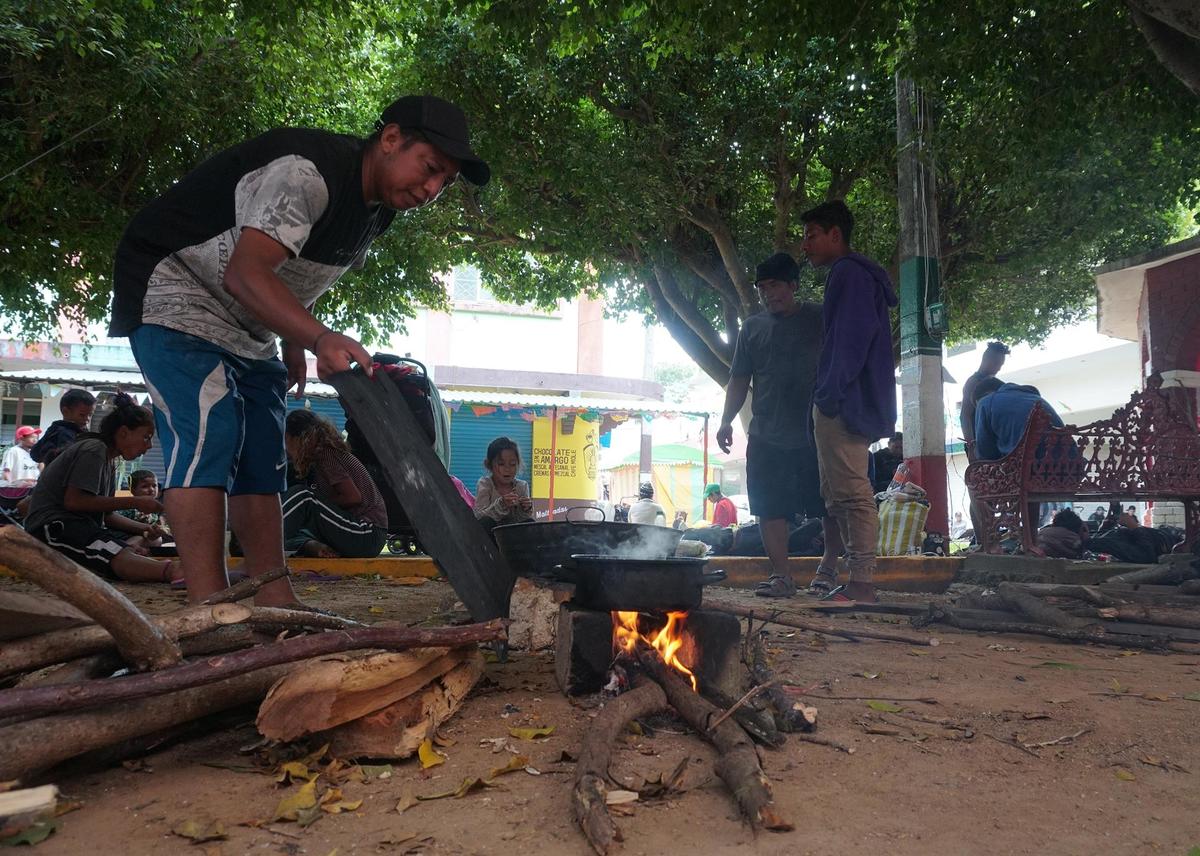 Migrantes cocinan en cubetas de fierro. (EFE)