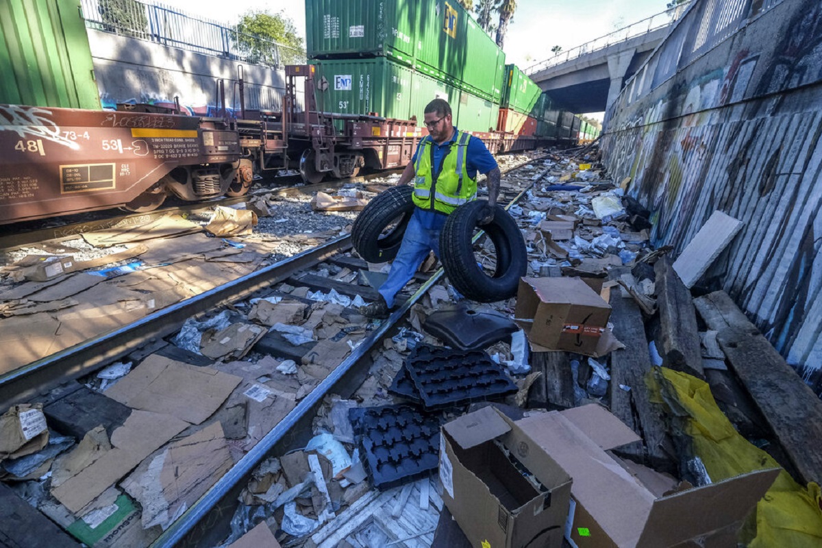 Trabajador limpia las vías llenas de paquetes robados. | AP