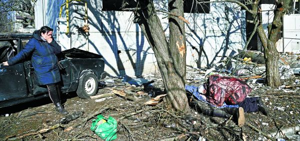 Una mujer observa el cadáver de un hombre tras un bombardeo en el pueblo de Chuguiv, en el oriente del país. AFP