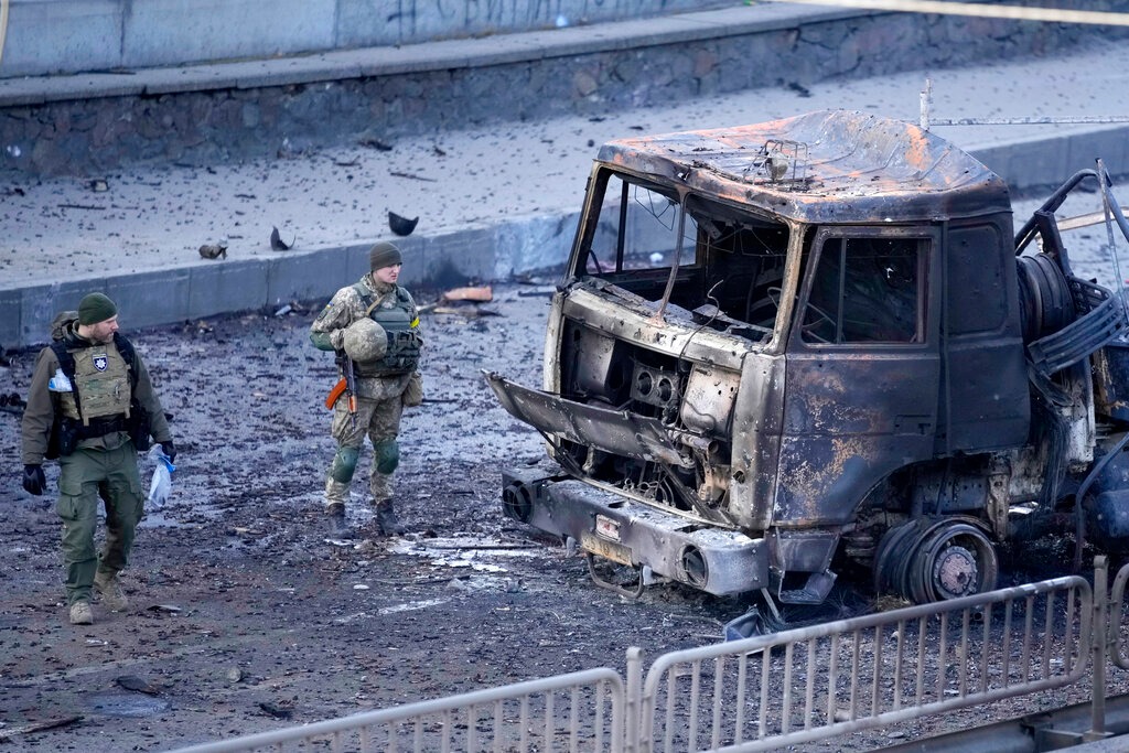 Un soldado ucraniano camina junto a los escombros de un camión militar en llamas | AP