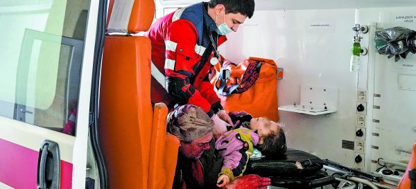 Un paramédico intenta salvar a una niña herida en la ciudad de Mariupol, junto a su padre (izq.). EFE