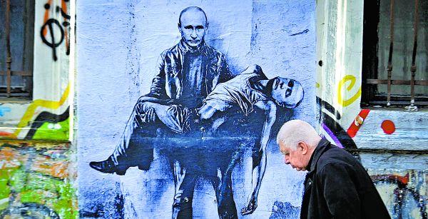 Un ciudadano pasa junto a una pintura mural que representa al presidente ruso sosteniendo su propio cuerpo. Nikolay Doychinov/AFP