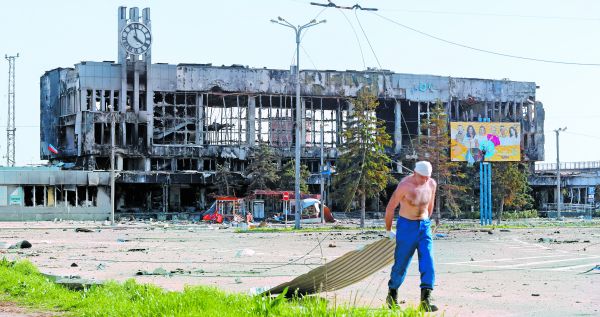 Un hombre arrastra una lámina cerca de las ruinas en la ciudad de Mariupol. Alexander Ermochenko/Reuters