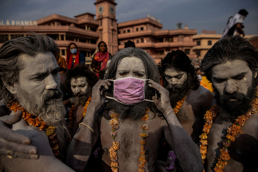 Un 'Naga Sadhu', hombre santo hindú, se coloca una máscara en la cara antes de ingresar al río Ganges. | Danish Siddiqui /Reuters