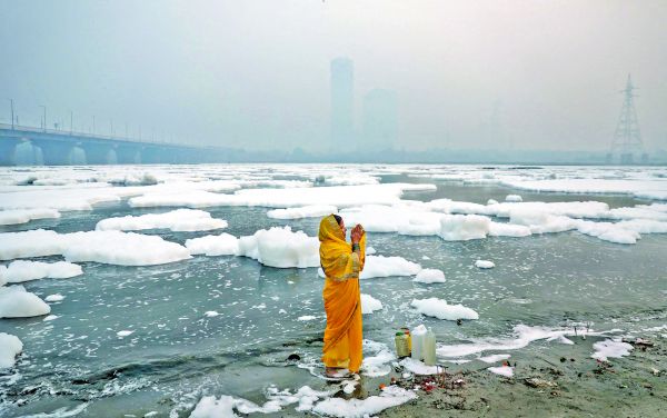 Una mujer reza a orillas del río contaminado Yamuna en una mañana llena de esmog en Nueva Delhi. Anushree Fadnavis/Reuters