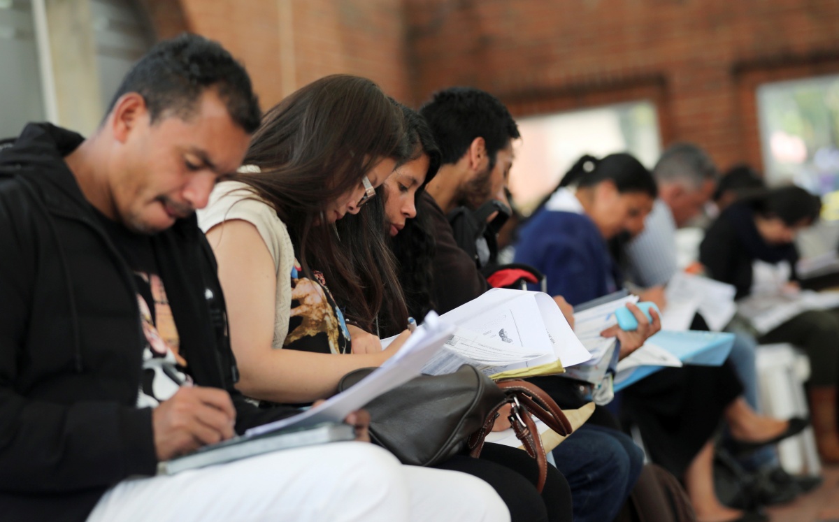 Personas llenan formatos para entregarlas durante una feria de empleo en Bogotá, Colombia, Mayo, 2019. Foto: (Reuters)