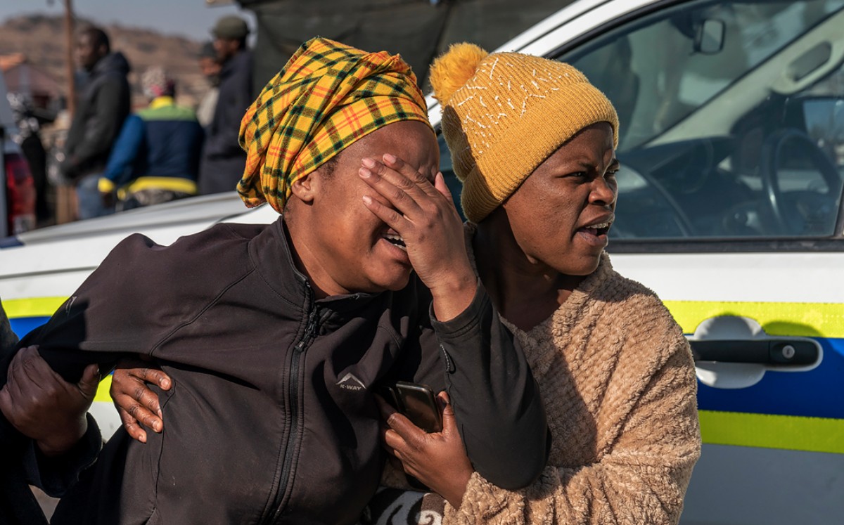 Mujeres lloran afuera de la taberna en el municipio de Soweto | AP